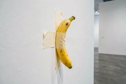 Banane collée avec du ruban adhésif sur un mur de galerie d'art contemporain blanc, représentant l'œuvre conceptuelle Comedian de Maurizio Cattelan